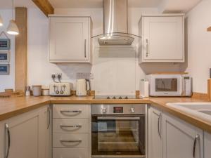 a kitchen with white cabinets and a stove top oven at Potters by the Sea in Penzance