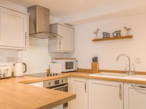 a kitchen with white cabinets and a sink and a microwave at Potters by the Sea in Penzance