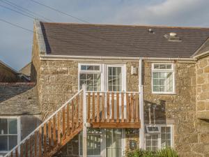 a stone house with a wooden porch and a deck at Potters by the Sea in Penzance