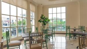 a restaurant with tables and chairs and windows at d'primahotel Pattimura Makassar in Makassar