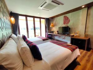 a hotel room with two beds and a television at Recall Isaan Isan Concept at Khaoyai SHA Extra Plus in Mu Si