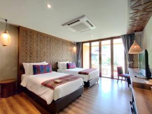 een hotelkamer met 2 bedden en een televisie bij Recall Isaan Isan Concept at Khaoyai SHA Extra Plus in Mu Si