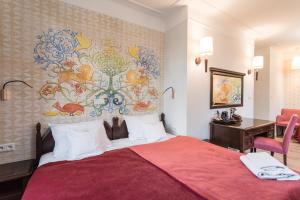 a bedroom with a red bed with a wall mural at Hotel Ester in Kraków