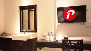 a bathroom with a sink and a tv on the wall at d'primahotel Pattimura Makassar in Makassar