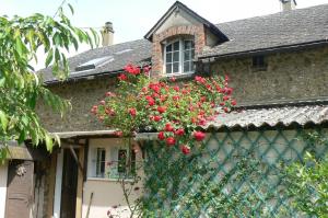 La grange في Alluyes: منزل به نافذة عليها زهور حمراء