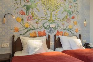 two beds in a bedroom with a floral wall at Hotel Ester in Kraków