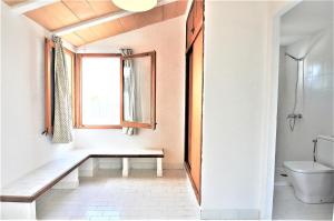 a bathroom with a bench and a window and a toilet at XOROI- Villa primera linea mar con vistas a Bahía Alcudia in Artá +55 photos
