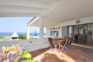 a dining room with a table and chairs and the ocean at XOROI- Villa primera linea mar con vistas a Bahía Alcudia in Artá