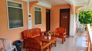 two wooden chairs and a table on a porch at WHITE BEACH GUEST HOUSE in Puerto Galera