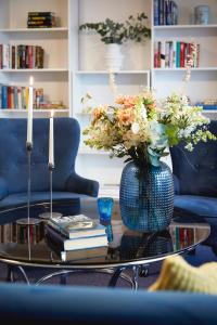 a blue vase with flowers on a table with books at Hotell Vesterhavet in Falkenberg