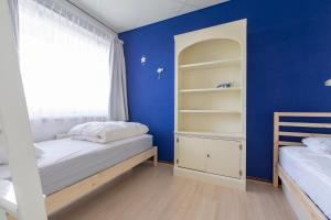 - une chambre avec 2 lits et un mur bleu dans l'établissement Strandslag 115 Beach Apartment, à Julianadorp
