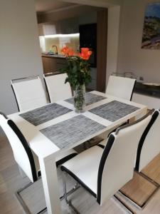 a white dining room table with a vase of orange flowers at APARTAMENT WŁODEK in Jelenia Góra