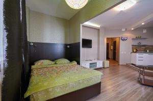 a bedroom with a bed with a green head board at Ochag Apartments in Magnitogorsk