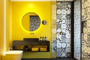 a yellow bathroom with a toilet and a mirror at Prinz Rudolf Smart Hotel in Merano