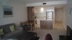ein Wohnzimmer und eine Küche mit einem Sofa und einem Tisch in der Unterkunft Manhattan on Glebe Park in Canberra