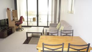 salon ze stołem, krzesłami i telewizorem w obiekcie Manhattan on Glebe Park w mieście Canberra