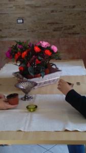 un tavolo con un vaso di fiori sopra, con una persona che tiene un foglio di Appartamenti Centro Policastro a Policastro Bussentino
