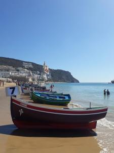 two boats sitting on the beach next to the water at Cezimbra Guest House in Sesimbra