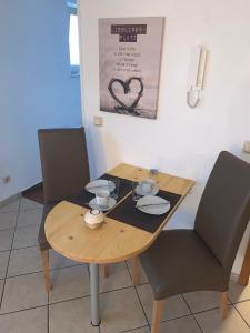 a wooden table with two chairs and a table with two cups at Ferienwohnung Sabine in Homburg