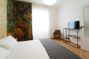 La Tigre Appartamento Con Terrazza In Centro في كالياري: غرفة نوم بسرير ابيض وتلفزيون