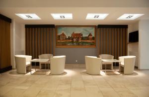 a waiting room with white chairs and a painting on the wall at Dedal in Malbork