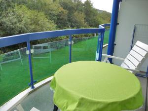 einen Balkon mit einem grünen Tisch und einem Stuhl in der Unterkunft Appartement 19 Callantsoog in Callantsoog