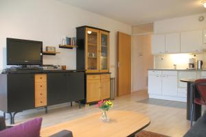 ein Wohnzimmer mit einem TV und einer Küche in der Unterkunft Appartement 19 Callantsoog in Callantsoog