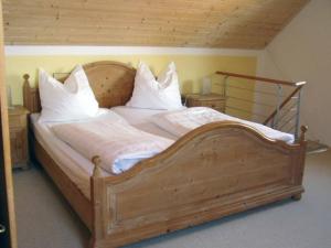a large wooden bed with white sheets and pillows at Ferienwohnung Hartinger in Wolfersdorf