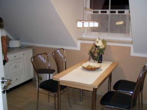 Ferienwohnung Hartinger في Wolfersdorf: مطبخ مع طاولة وكراسي مع وعاء من الزهور عليه