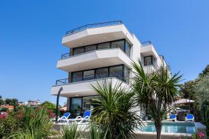 a tall white building with chairs and a swimming pool at Kevin in Pješčana Uvala