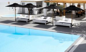 een zwembad met ligstoelen en parasols naast een zwembad bij Kalisti Hotel & Suites in Fira