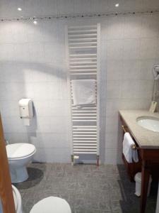a white bathroom with a toilet and a sink at Hôtel Restaurant Le Bristol in Niederbronn-les-Bains