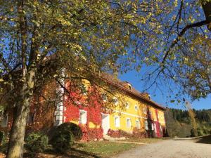 a yellow and red building with a tree in front of it at Ferienwohnung Ottmanach Schlosshof in Pischeldorf