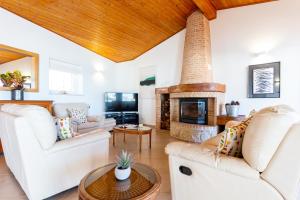 a living room with white furniture and a brick fireplace at Casa Bom Porto in Luz