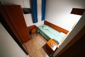 1 dormitorio pequeño con 1 cama y 1 silla en Hostal Restaurante El Surtidor, en Caspe