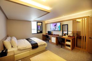 Schlafzimmer mit einem Bett und einem Schreibtisch mit einem Computer in der Unterkunft Hotel Two Heart in Daegu