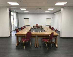 una sala conferenze con un grande tavolo e sedie in legno di Hôtel Restaurant Kyriad Direct DIJON NORD - Zenith - Toison d'Or a Digione