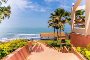 a walkway to the beach with a building and palm trees at Tropic Garden Hotel in Banjul