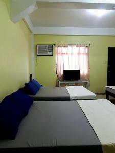 a bedroom with two beds and a window with a laptop at Hundred Islands lucky One Transient 3mins walk fr wharf in Alaminos