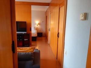 - un couloir d'une chambre d'hôtel avec un canapé et une télévision dans l'établissement Barceló Cornellà, à Cornellà de Llobregat