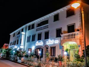 Un bâtiment blanc avec des lumières allumées la nuit dans l'établissement Hotel Smeraldo, à Isola Rossa