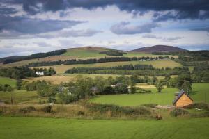 a green hillside with a house in a green field at Isla Pod, Kilry eco pods in Blairgowrie