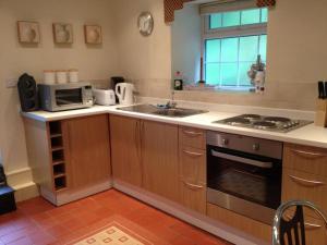 a kitchen with a stove and a sink and a microwave at Red Dragon Holidays in Beddgelert