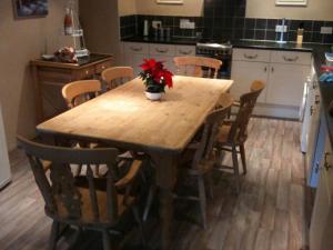 a kitchen with a wooden table with a vase of flowers on it at Red Dragon Cottages nr Mt Snowdon in Beddgelert +81 photos