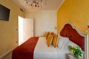 Un dormitorio con una cama grande con paredes amarillas y una lámpara de araña. en Relais Empire, en Verona