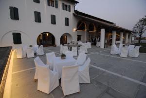 a group of white tables and chairs in front of a building at Casa dei Racconti in Ceggia