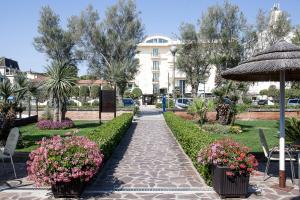 a walkway through a park with flowers and an umbrella at Hotel Nettuno in Cervia