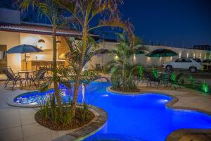 ein Pool mit Palmen und Tischen in der Nacht in der Unterkunft Juazeiro Comfort Hotel in Juazeiro do Norte