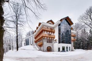 a large building in the snow with trees at Zamek Księża Góra in Karpacz