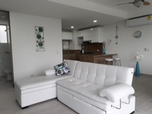 a white couch in a living room with a kitchen at SANTA MARTA OASIS en ZAZUE in Santa Marta